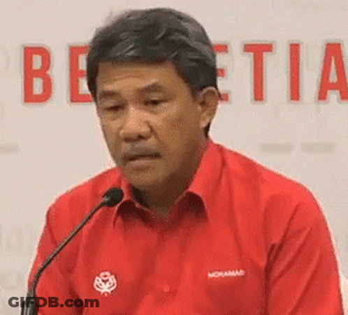 A Man In A Red Shirt Is Sitting At A Microphone . GIF