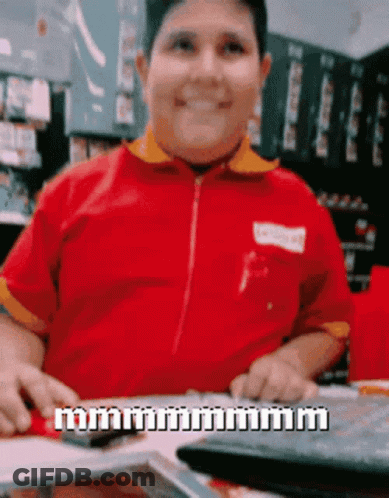 A Man In A Red Shirt Is Sitting At A Table With A Keyboard And A Calculator GIF
