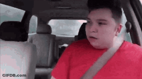 A Man In A Red Shirt Is Sitting In A Car . GIF