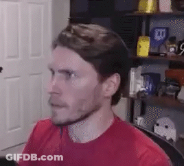 A Man In A Red Shirt Is Sitting In A Chair In Front Of A Computer . GIF