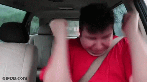 A Man In A Red Shirt Is Sitting In The Back Seat Of A Car GIF