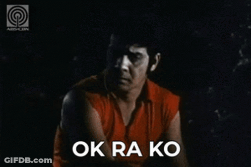 A Man In A Red Shirt Is Sitting In The Dark With The Words Ok Ra Ko Above Him GIF