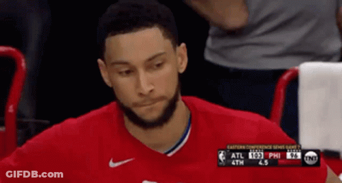 A Man In A Red Shirt Is Sitting In The Stands Watching A Game GIF