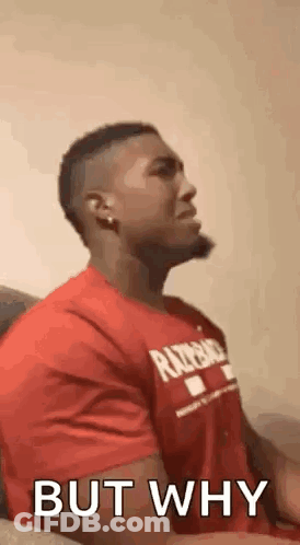 A Man In A Red Shirt Is Sitting On A Couch And Talking To Someone . GIF