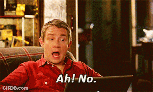 A Man In A Red Shirt Is Sitting On A Couch Looking At A Laptop And Saying Ah No GIF