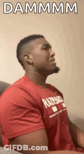 A Man In A Red Shirt Is Sitting On A Couch With His Eyes Closed And The Words Dammmm Written Above Him . GIF