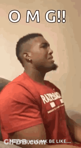A Man In A Red Shirt Is Sitting On A Couch With His Mouth Open . GIF