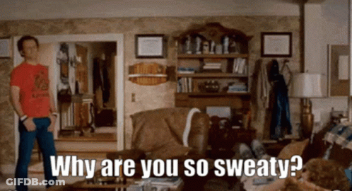 A Man In A Red Shirt Is Standing In A Living Room Asking Why Are You So Sweaty . GIF