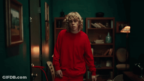 A Man In A Red Shirt Is Standing In A Room GIF
