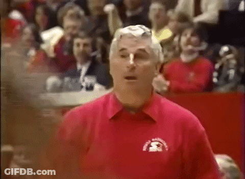 A Man In A Red Shirt Is Standing In Front Of A Crowd In A Stadium . GIF