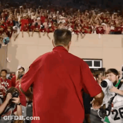 A Man In A Red Shirt Is Standing In Front Of A Crowd With The Number 28 On His Jersey GIF