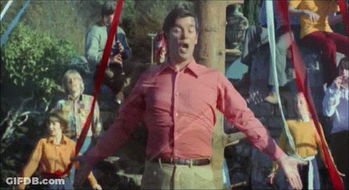 A Man In A Red Shirt Is Standing In Front Of A Group Of People GIF