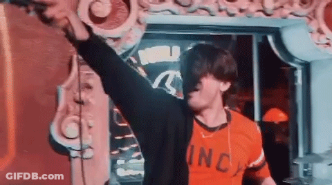 A Man In A Red Shirt Is Standing In Front Of A Mirror With His Arms In The Air . GIF