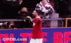 A Man In A Red Shirt Is Standing In Front Of A Sign That Says ' U ' On It GIF