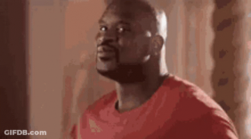 A Man In A Red Shirt Is Standing In Front Of A Window And Looking Up . GIF