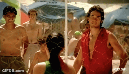 A Man In A Red Shirt Is Standing Next To A Woman In A Green Tank Top GIF