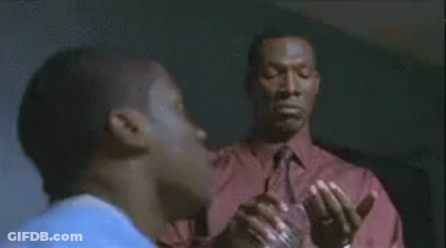 A Man In A Red Shirt Is Standing Next To Another Man In A Room . GIF