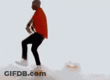 A Man In A Red Shirt Is Standing On A Pile Of Ice GIF