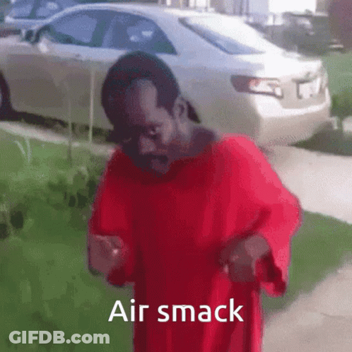 A Man In A Red Shirt Is Standing On A Sidewalk With The Words Air Smack Above Him . GIF