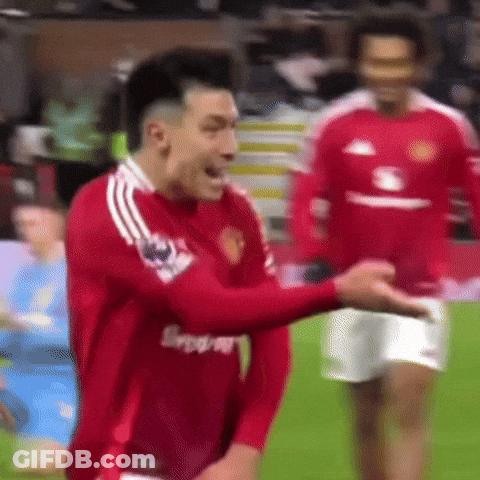 A Man In A Red Shirt Is Standing On A Soccer Field With His Hands In His Pockets . GIF