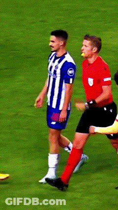 A Man In A Red Shirt Is Standing On A Soccer Field With Players GIF