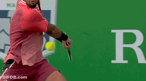 A Man In A Red Shirt Is Swinging A Tennis Racket GIF