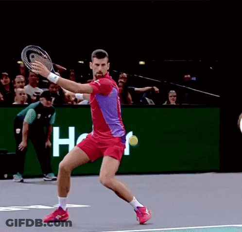 A Man In A Red Shirt Is Swinging A Tennis Racquet GIF