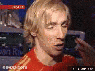 A Man In A Red Shirt Is Talking In Front Of A Sign That Says Just In On It GIF