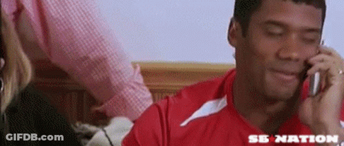 A Man In A Red Shirt Is Talking On A Cell Phone With The Word Se Nation On The Bottom GIF