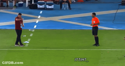 A Man In A Red Shirt Is Talking To A Referee On A Soccer Field With Ittih7 Written On The Bottom GIF