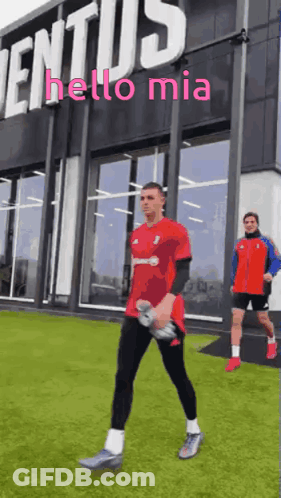 A Man In A Red Shirt Is Walking In Front Of A Building That Says " Hello Mia " GIF