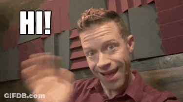 A Man In A Red Shirt Is Waving His Hand In Front Of A Wall That Says Hi . GIF