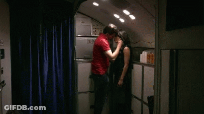 A Man In A Red Shirt Kisses A Woman In A Kitchen GIF
