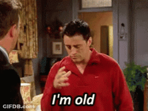 A Man In A Red Shirt Says I 'M Old While Talking To Another Man GIF