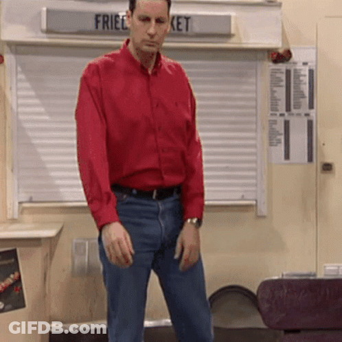 A Man In A Red Shirt Stands In Front Of A Sign That Says Fried Bucket GIF