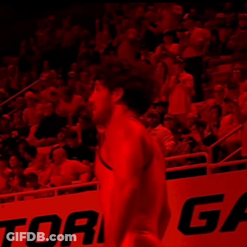 A Man In A Red Shirt Stands In Front Of A Sign That Says Ric GIF