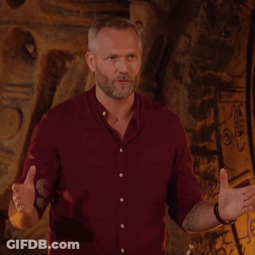 A Man In A Red Shirt Stands In Front Of A Wall With The Word Survivor On It GIF