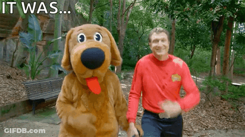 A Man In A Red Shirt Stands Next To A Stuffed Dog With The Words " It Was " Written On The Bottom GIF