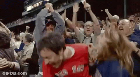 A Man In A Red Shirt That Says ' Boston ' On It Is Dancing In A Crowd Of People GIF