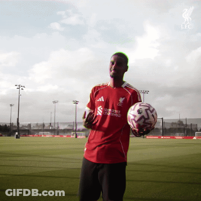A Man In A Red Shirt That Says Standard Chartered On It Holds A Soccer Ball GIF