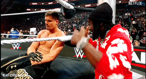 A Man In A Red Shirt With The Letter A On It Is Talking To Another Man In A Wrestling Ring GIF