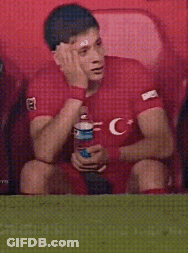 A Man In A Red Shirt With The Letter C On It Sits On The Field GIF