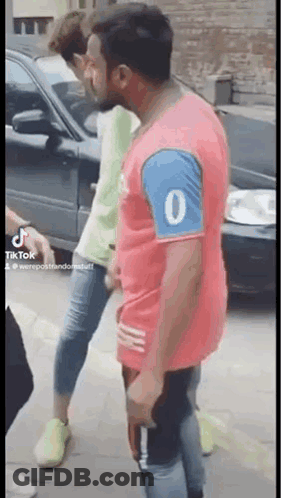 A Man In A Red Shirt With The Number 0 On The Sleeve Is Standing Next To Another Man In A Green Shirt . GIF