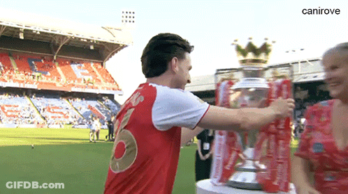 A Man In A Red Shirt With The Number 8 On The Back Is Hugging A Trophy GIF