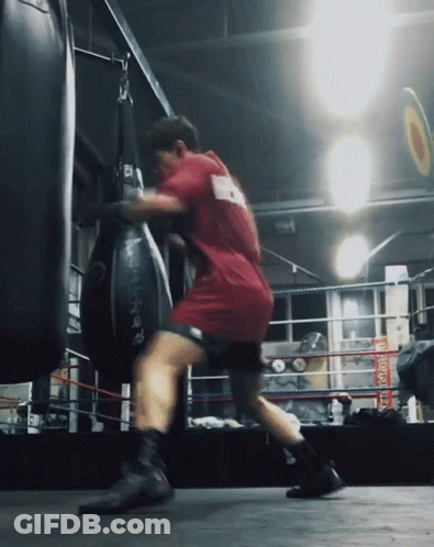A Man In A Red Shirt With The Number 9 On The Back Is Punching A Bag GIF