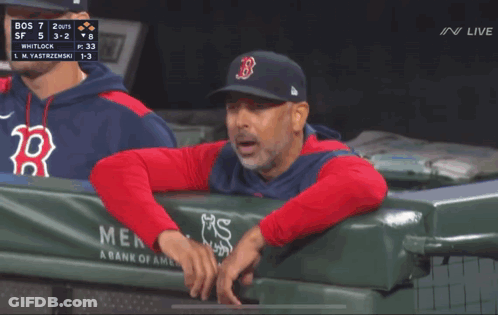 A Man In A Red Sox Hat Is Pointing At The Scoreboard GIF