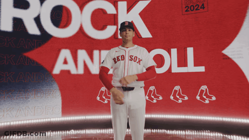 A Man In A Red Sox Jersey Stands In Front Of A Boston 2024 Poster GIF