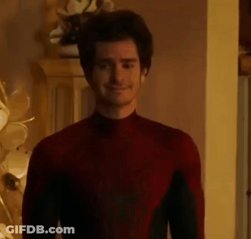 A Man In A Red Spiderman Costume Is Standing In A Room And Smiling . GIF