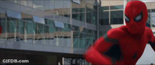 A Man In A Red Spiderman Suit Is Standing In Front Of A Building GIF