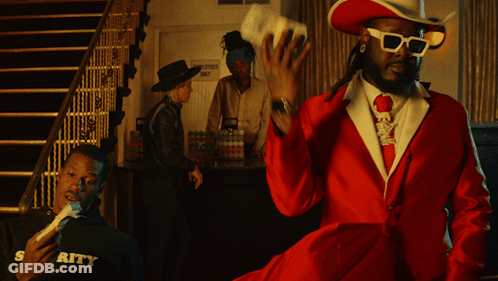 A Man In A Red Suit And Cowboy Hat Stands In Front Of A Sign That Says Employment Only GIF